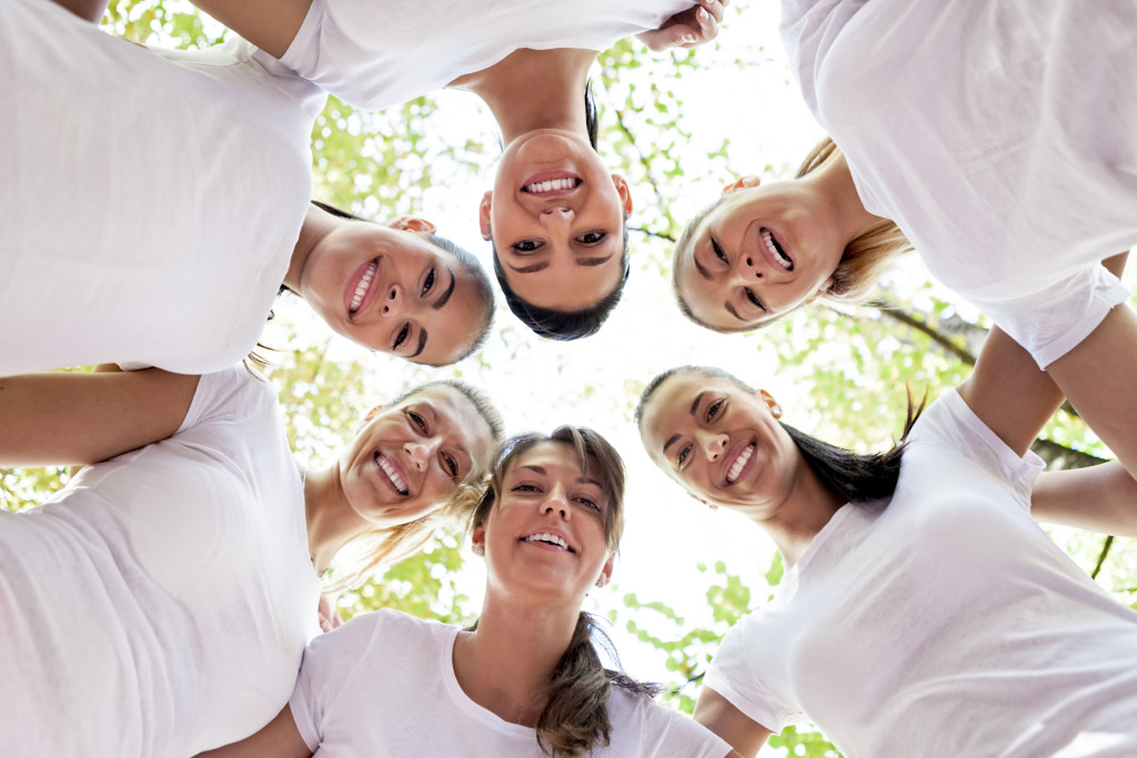 Group of women standing in the circle, smiling at the camera, low angle view.